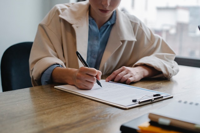 woman writing on clipboard