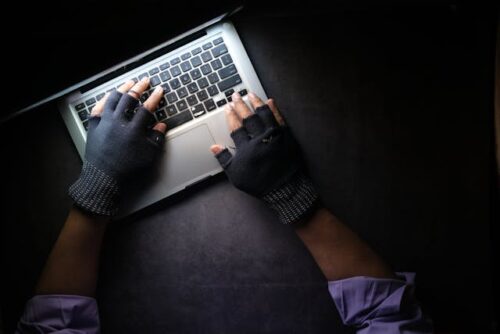 person in gloves typing on computer